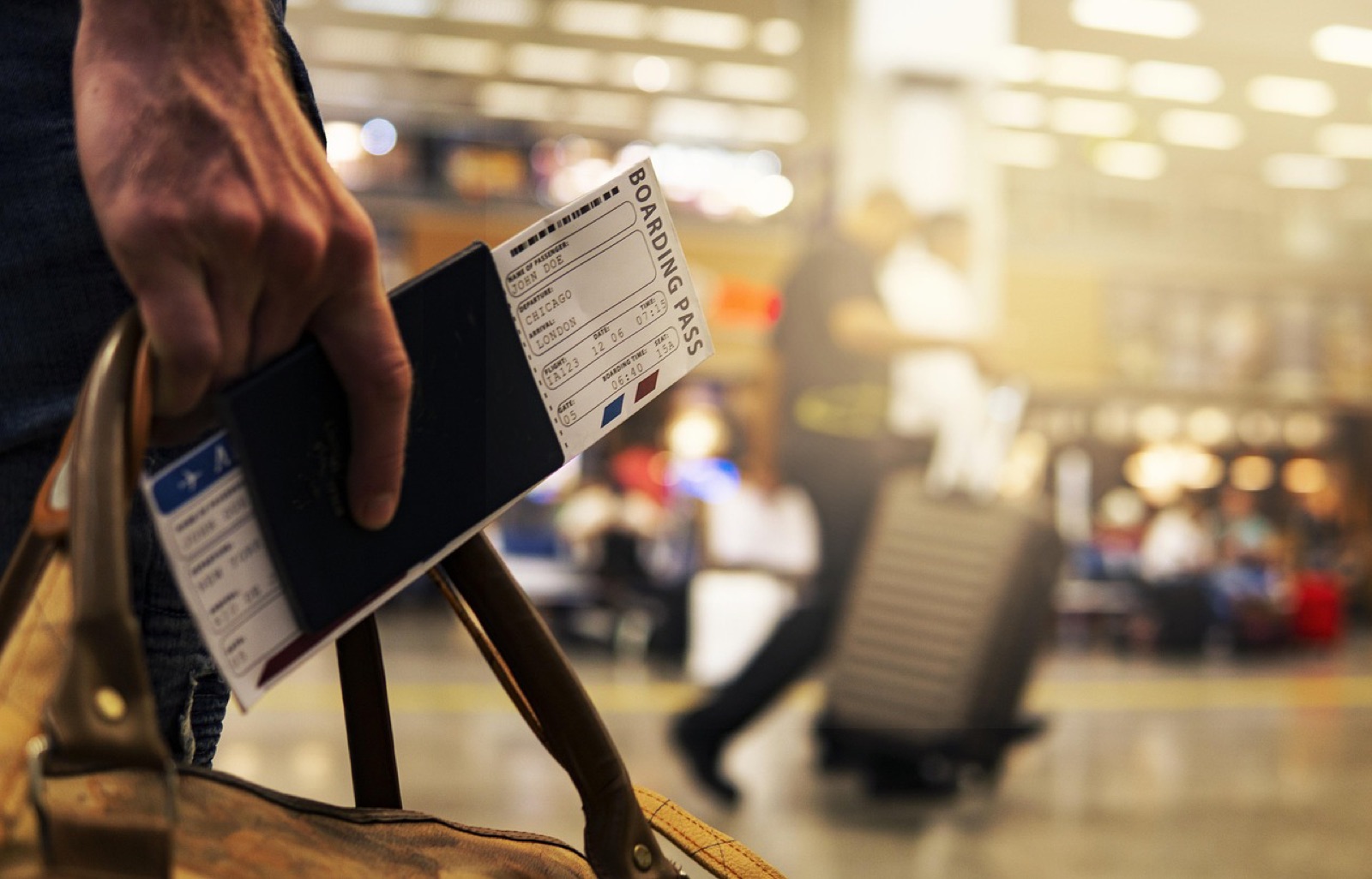 Traveler holding a passport and boarding pass inside a busy airport terminal