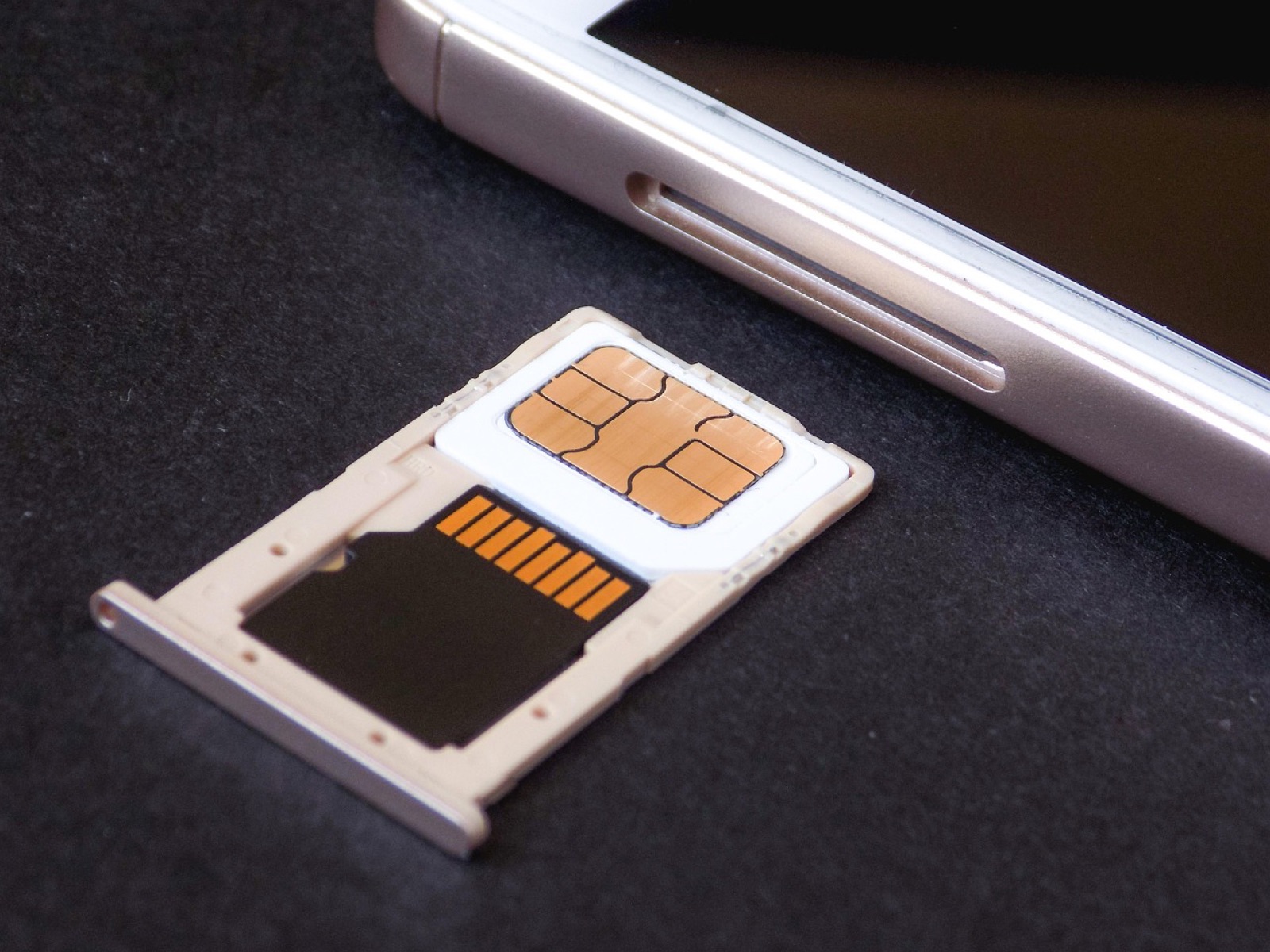 Smartphone SIM tray with a nano SIM card and memory card on a dark table