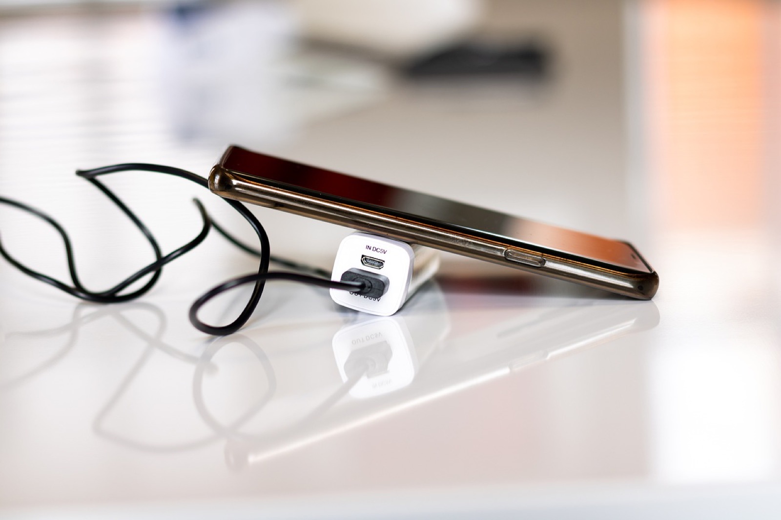 Smartphone lying on a table next to a white charger and cable