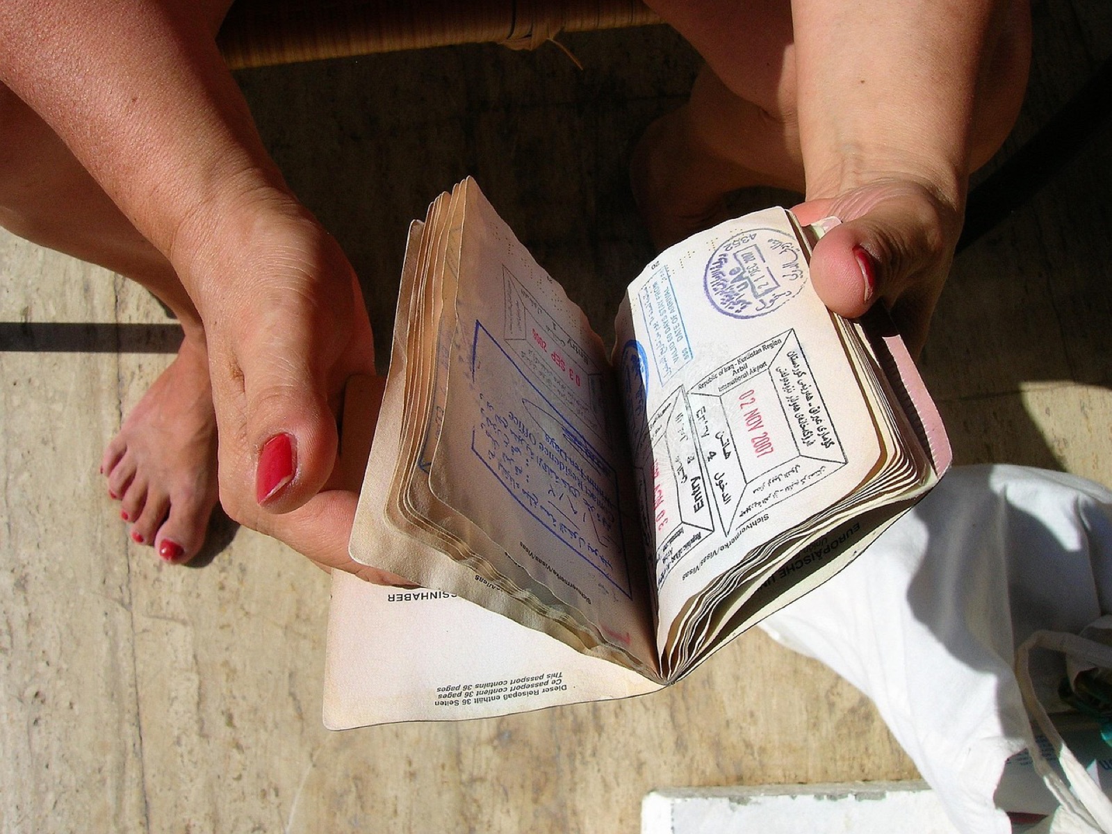 Hands flipping through passport pages filled with entry stamps