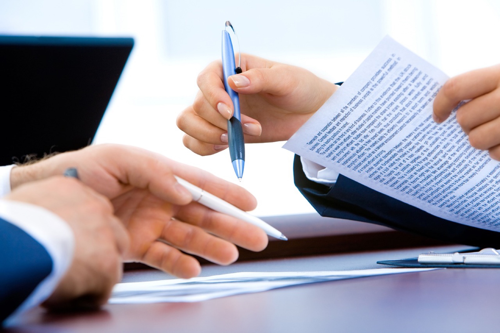 Two people reviewing a printed document with pens at a desk