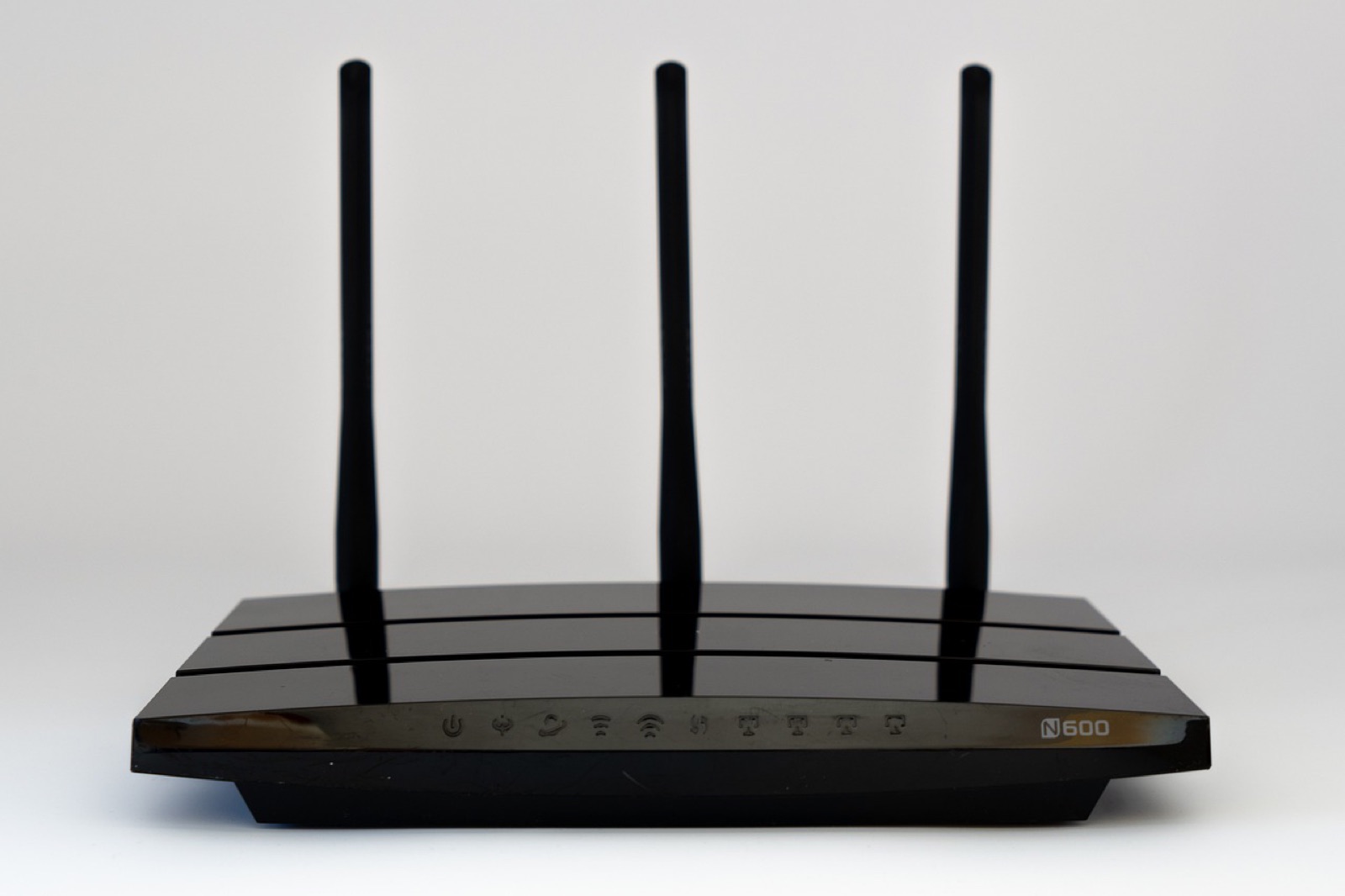 Black wireless router with three antennas on a white background
